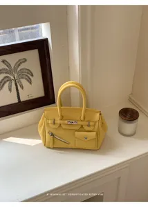 Yellow leather handbag with structured top handles, metal turn-lock, and chic front pockets.