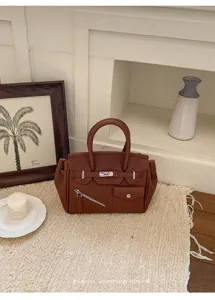 Chic brown leather handbag detail featuring dual top handles and unique zipper pocket styles.