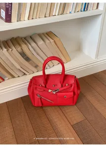 Red leather handbag with top handle and classic turn-lock closure for daily commute.