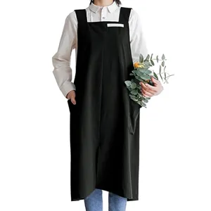 Japanese style long black apron detail shot, wearing over shirt, convenient deep side pockets.