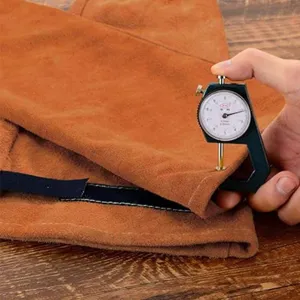 Close-up detail shot of brown leather welding sleeve material thickness measurement tool view.
