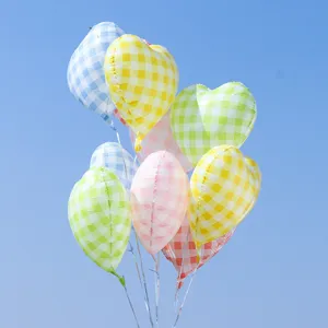 Detailed close-up shot of colorful checkered heart-shaped foil balloons floating against blue sky.