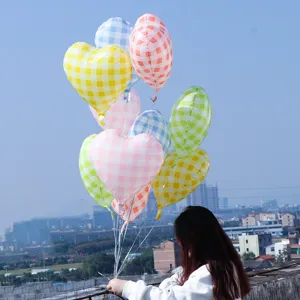 Outdoor scenic detail of colorful plaid heart aluminum film balloons held against blue sky.
