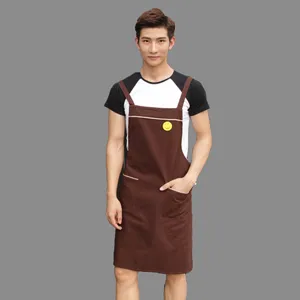 Unisex brown work apron with pockets and smiley badge, durable polyester-cotton fabric.