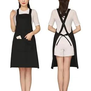 Black cross-back work apron with pockets, adjustable straps, durable fabric for kitchen coffee shop.