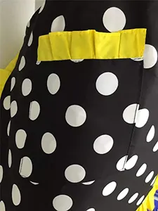Retro black and white polka dot apron with yellow ruffle pockets, perfect for kitchen and work.