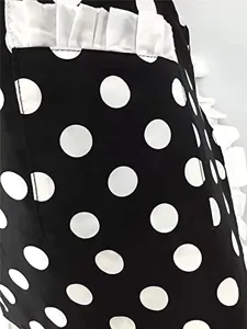 Close-up detail of black and white polka dot apron with white ruffle pocket trim.