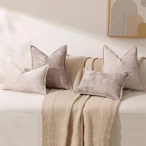 Vue détaillée de coussins décoratifs en velours chenille luxueux sur un canapé beige, déco cosy.