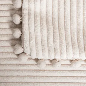 Close-up detail of beige corduroy throw pillow cover with cute pom-pom trim texture fabric.