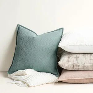 Detail view of chenille chevron decorative throw pillow and stacked cushions on display.