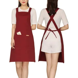 Cross-back kitchen apron with adjustable straps and front pocket for barista and cafe work.