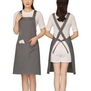 Grey cross-back apron with pockets, adjustable straps, durable workwear for kitchen or cafe.
