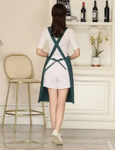 Green cross back apron with adjustable straps, premium workwear for kitchen and coffee shop.