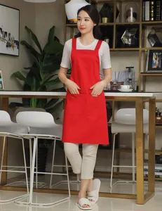 Red kitchen apron with cross back straps and front pockets, ideal for cooking, baking or cafe work.