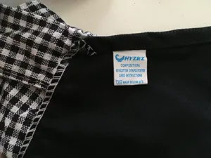 Apron detail view showing black and white checkered fabric and care label with composition.