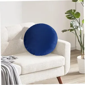 Detailed view of a dark blue round velvet throw pillow on a cozy sofa, soft texture.