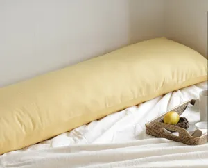 Vue detaillee du long oreiller de corps jaune dans une chambre confortable et douce.