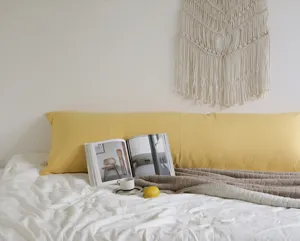 Détail de tissu doux oreiller long jaune dans une scène de chambre minimaliste confortable.