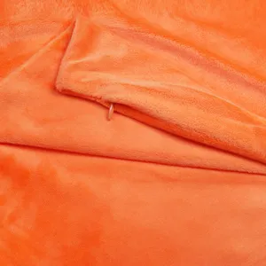 Gros plan sur la texture de la housse de coussin en peluche orange douce et confortable.