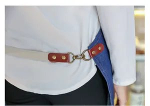Gros plan sur la sangle de tablier en jean et la boucle métallique, coutures solides et design.