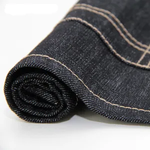 Tissu denim foncé de première qualité en gros plan avec coutures jaunes contrastées robustes.