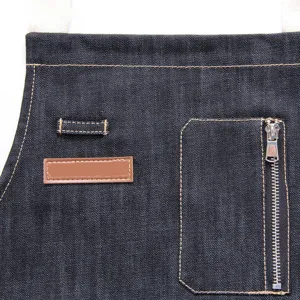 Tablier de travail en denim foncé avec poche zippée et boucles pour cuisine et barbecue.