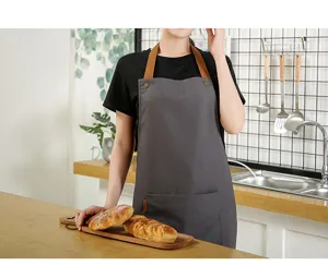 Detailed view of kitchen apron canvas texture with brown strap and front pocket setup.