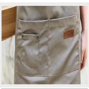 Gros plan sur la poche du tablier en toile de coton, coutures solides et design utilitaire.