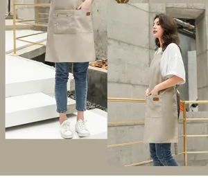 Vue détaillée du tablier de travail en toile de coton kaki avec poches avant pratiques.