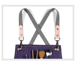 Canvas work apron detail featuring adjustable cross-back straps, metal hardware and deep pockets.