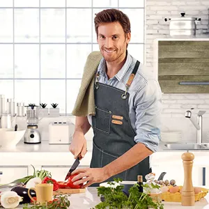 Canvas kitchen apron with adjustable leather straps and pockets, ideal for cooking, grilling.