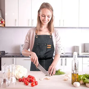 Close-up view of a durable canvas cooking apron featuring handy pockets and stylish straps in kitchen.