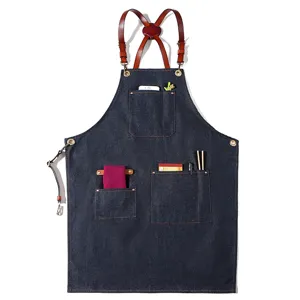 Classic dark blue denim work apron with brown leather cross-back straps and multi functional pockets.