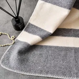 Grey and white striped knitted throw blanket detail, soft woolen sofa blanket texture.