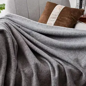 Cozy grey knitted throw blanket detail, soft woolen texture for sofa and office use.