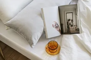 Grey velvet pillow detail showing soft short plush texture on white bedding with cozy props.