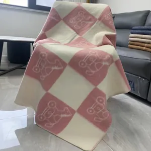 Knitted wool blend sofa throw blanket with pink and white checkered rocking horse pattern.