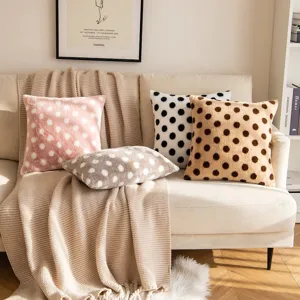 Cozy polka dot plush throw pillow and soft knitted blanket sofa scene interior decor.