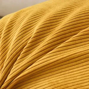 Primo piano dettagliato di un tessuto per cuscino in corduroy giallo a righe fini.