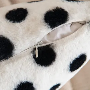 Close-up of black and white polka dot plush pillow, soft faux rabbit fur fabric detail.