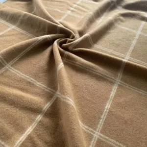 Detailed close-up view of soft camel wool blend plaid blanket fabric texture and drape.