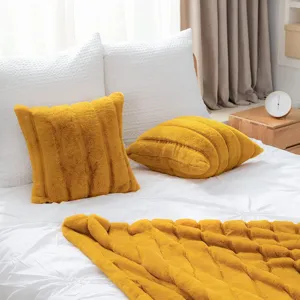 Yellow faux fur plush pillow cushion and matching throw blanket detail view in bedroom setup.