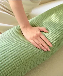 Close up of waffle weave body pillow texture, soft and cooling green cylinder pillow detail.