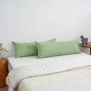 Corduroy long body pillow detail view showcasing soft green striped texture placed on the bed.