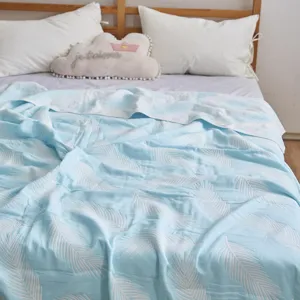 Gros plan détaillé de la couverture en gaze de coton douce avec motif de plumes bleues.