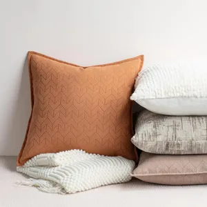 Detail view of textured chenille throw pillow and knit blanket in cozy home decor setup.