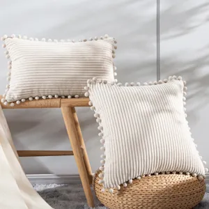 Corduroy throw pillow with pom pom fringe, soft decorative cushion for sofa, bed, and living room.