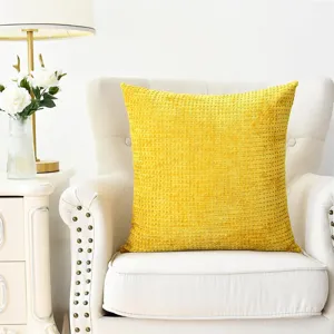 Detail shot of a bright yellow textured waffle chenille throw pillow on a white chair.