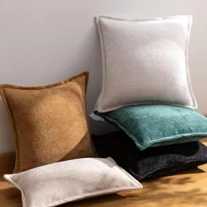 Vue détaillée de coussins moelleux en chenille empilés sur sol en bois, déco salon.