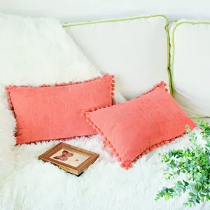 Coussin de canapé décoratif en chenille rose corail avec de jolies franges pompons.